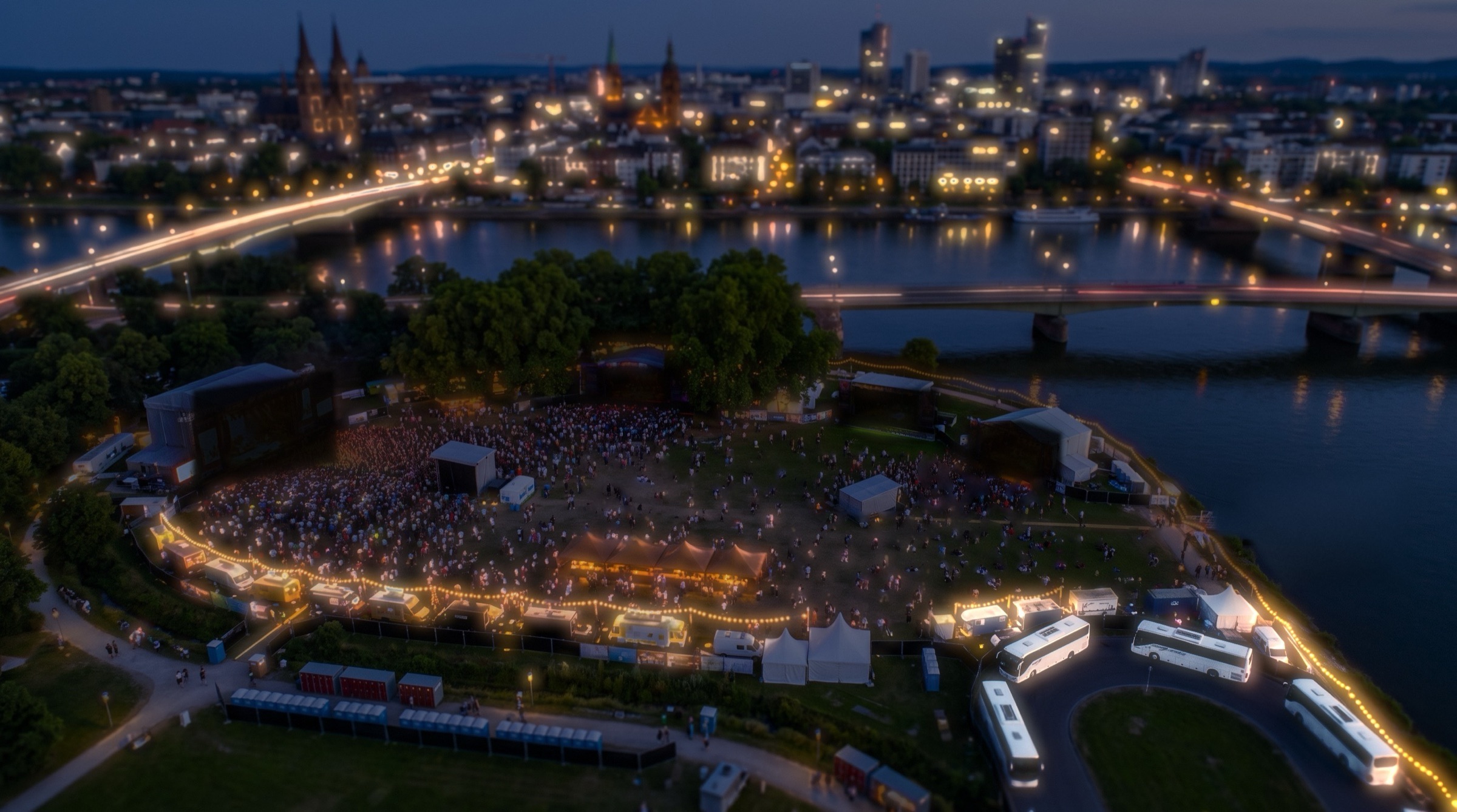 The same park at night, stages dark, buses lit at the gate
