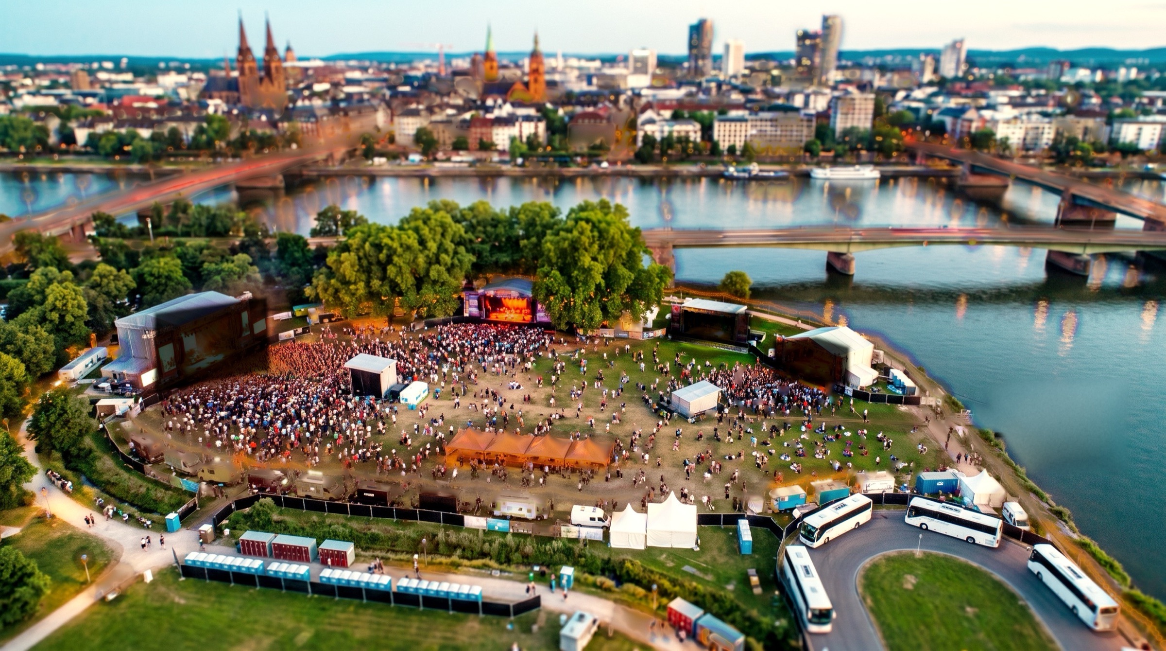 The same park in the afternoon sun, the stage under the trees lit and playing