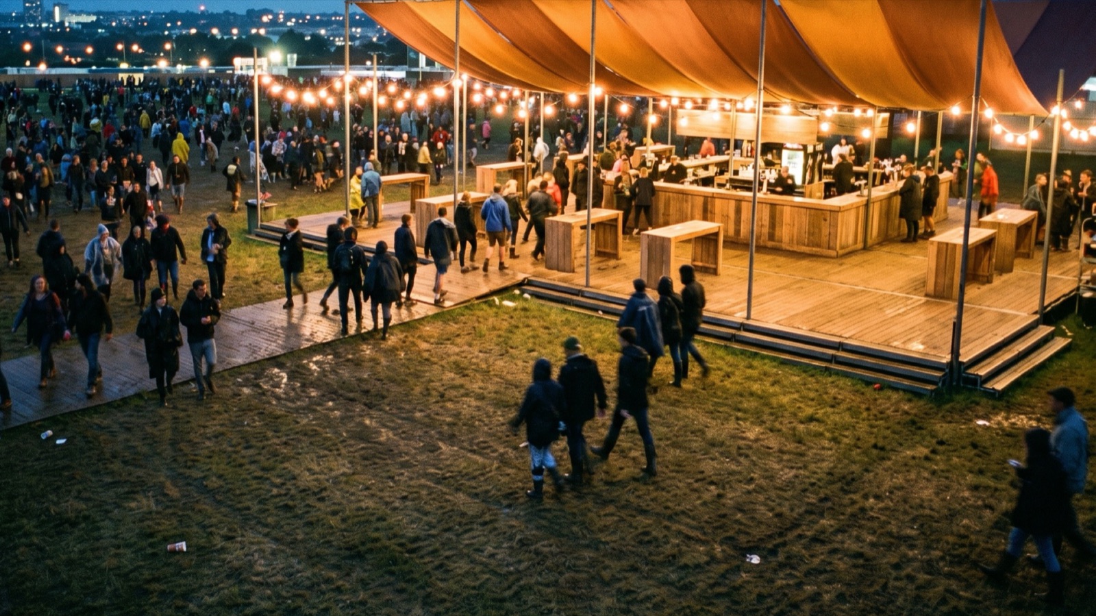A busy sponsor bar at dusk: people walk onto the deck under a copper canopy and festoon lights