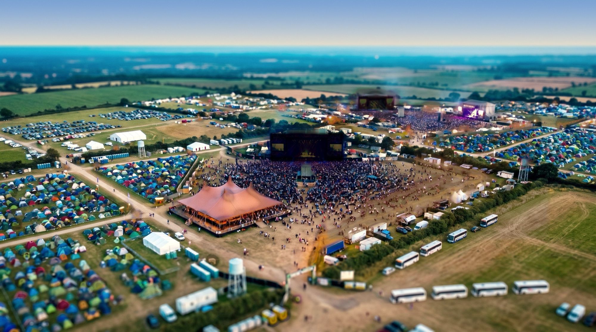 The same view in warm afternoon light: the East Stage lit and playing, the Main Stage dark.