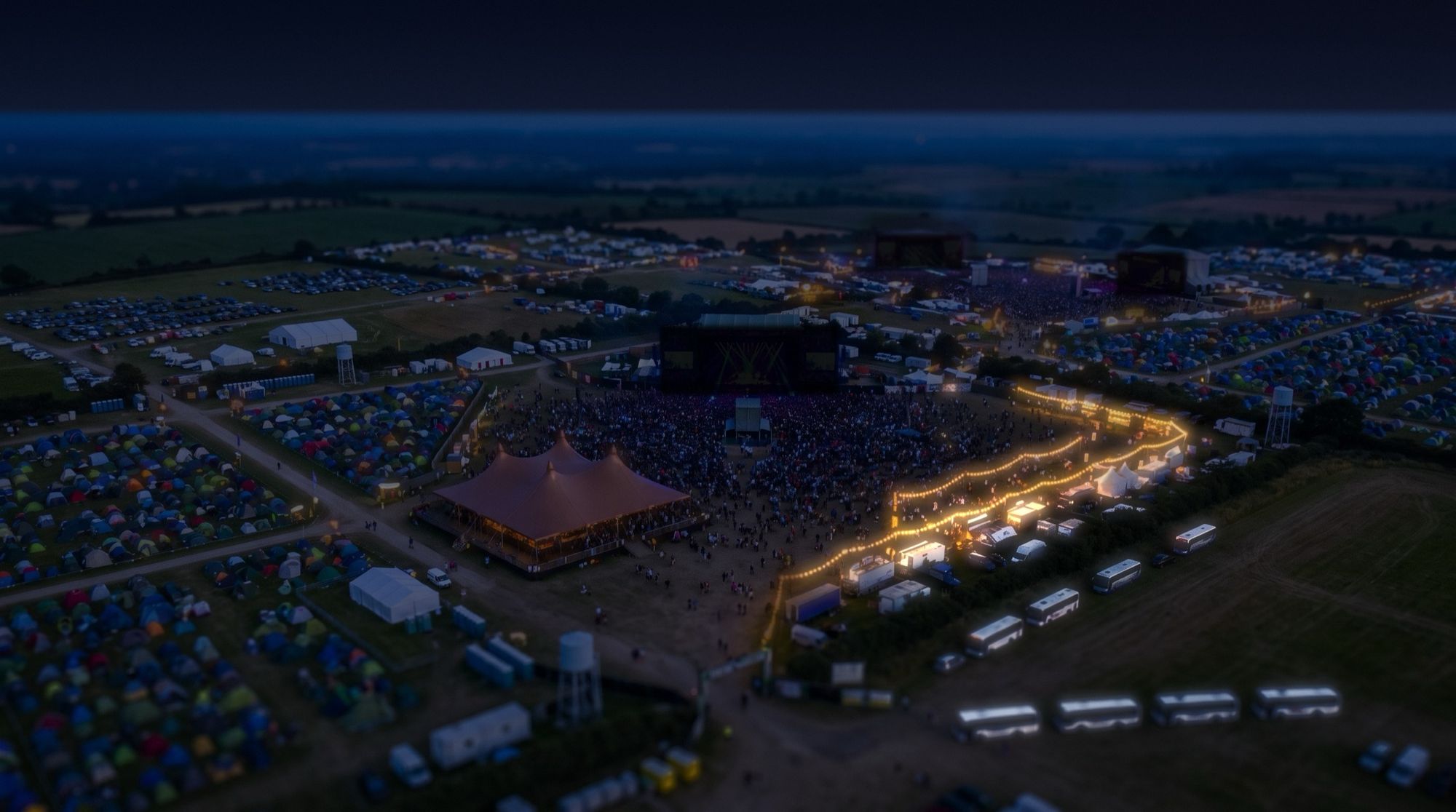 The same view at night: stages dark, the coaches lit by the gate.