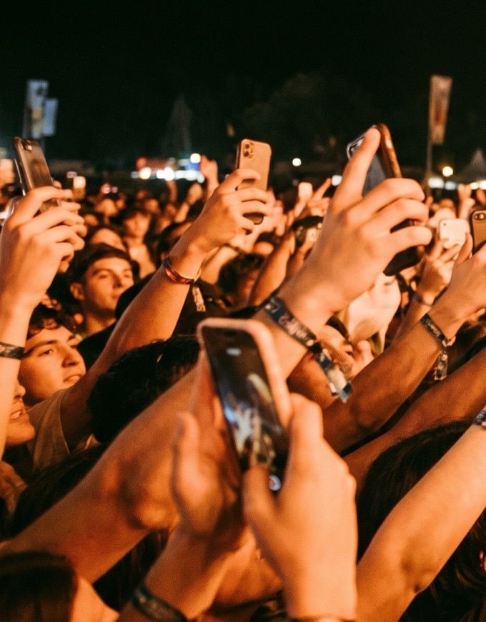Fans at the barrier at night, phones up.
